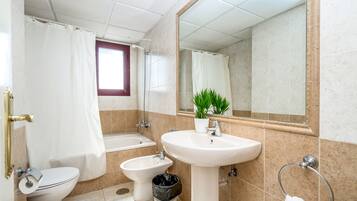 Un baño con inodoro, bidé, lavamanos y bañera.