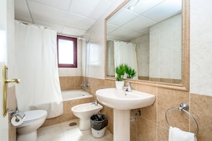 A bathroom with a toilet, bidet, sink, and bathtub.