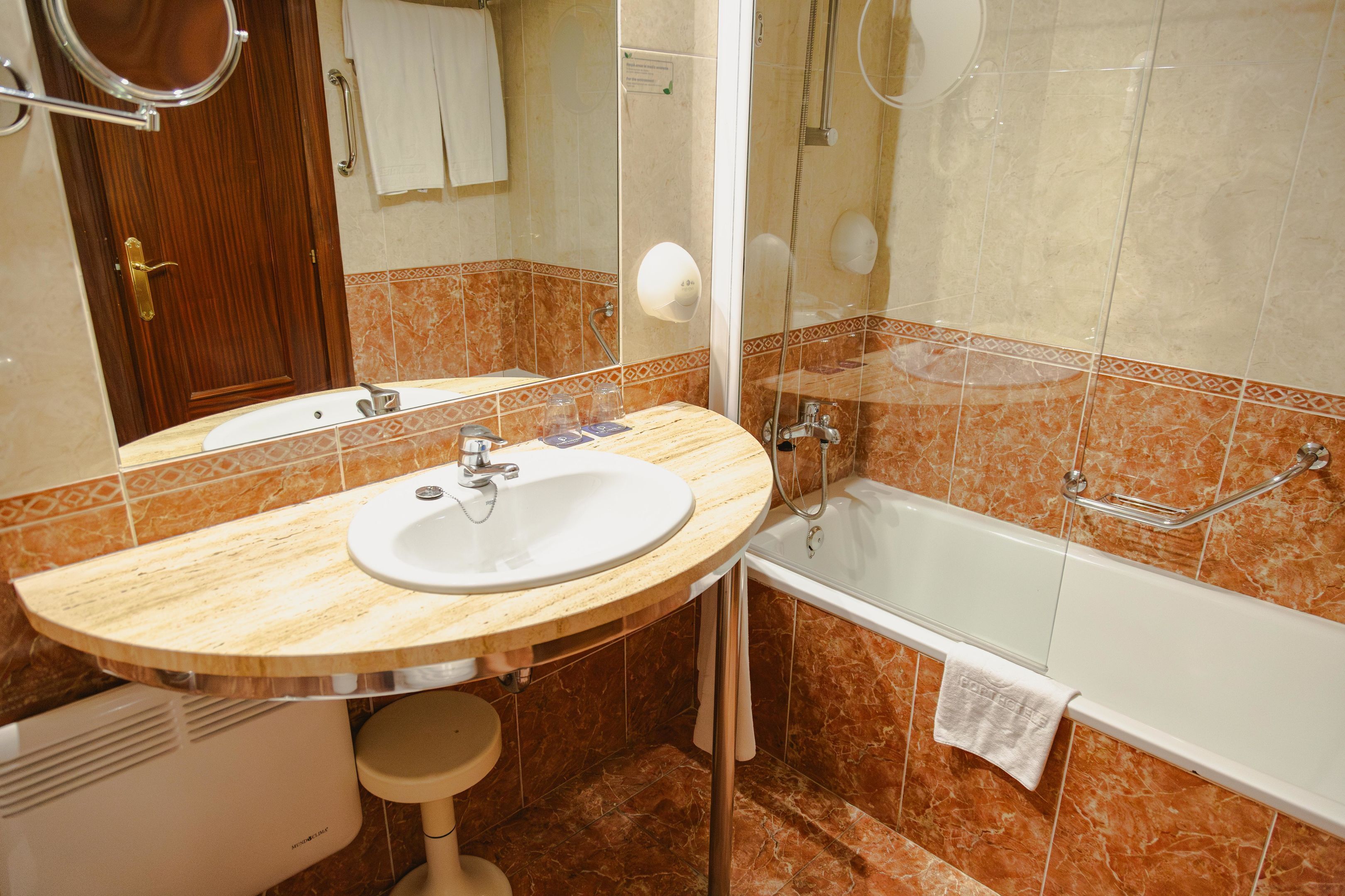 Un baño con lavamanos, espejo y bañera.