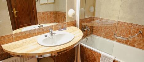 Un baño con lavamanos, espejo y bañera.