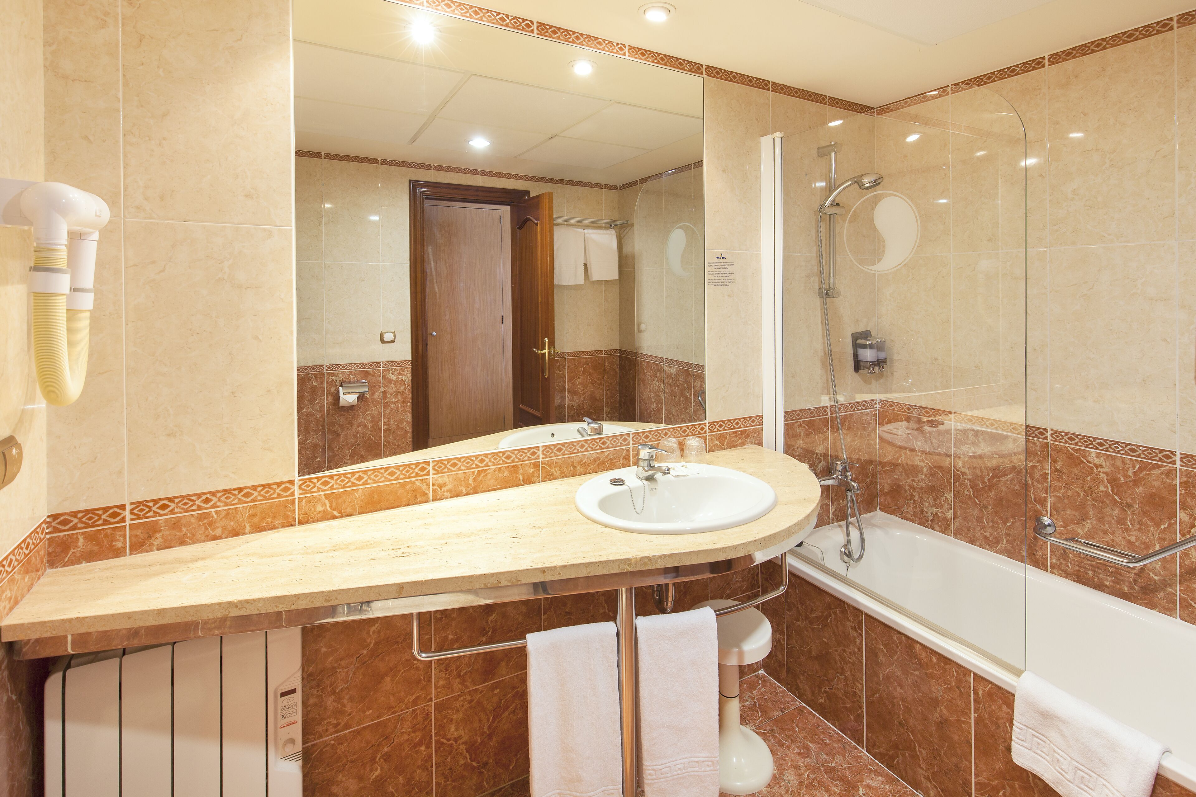 A bathroom with a sink, mirror, shower, and towel rack.