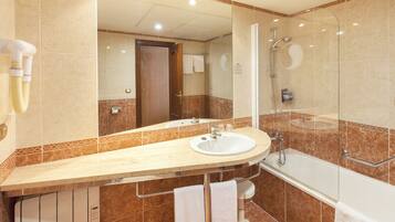 A bathroom with a sink, mirror, shower, and towel rack.