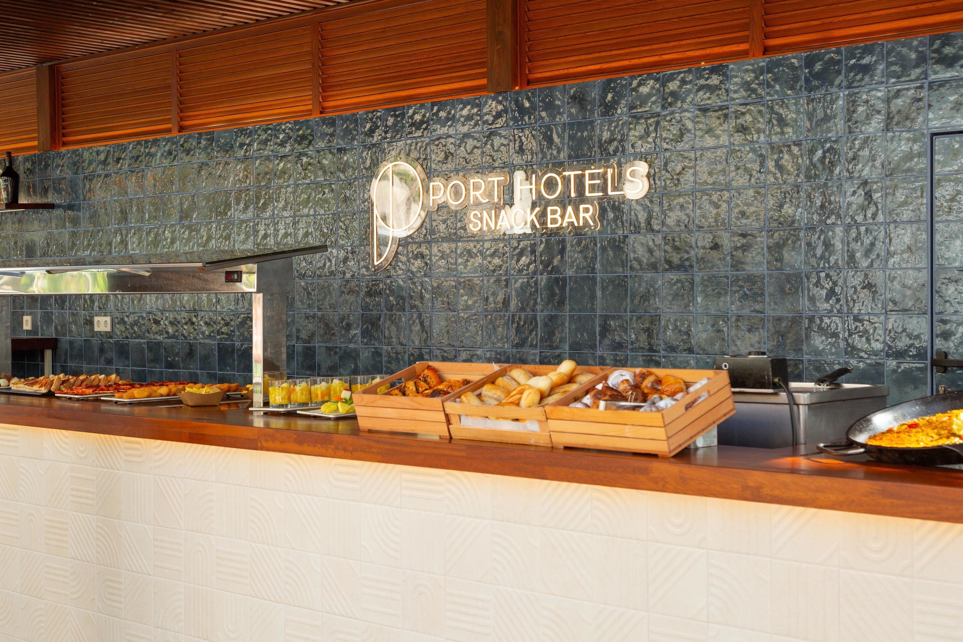 A buffet counter with a variety of food items and a sign for Port Hotels Snack Bar.