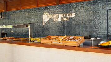 A buffet counter with a variety of food items and a sign for Port Hotels Snack Bar.