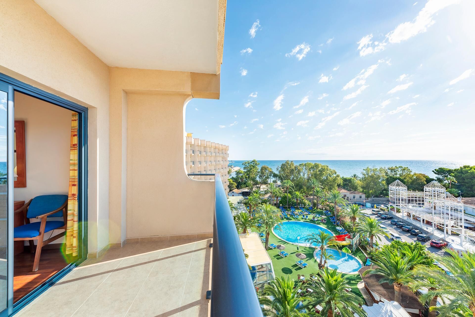 A balcony with a view of a pool area, including a water slide and lounge chairs.