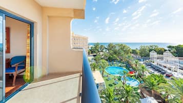 A balcony with a view of a pool area, including a water slide and lounge chairs.