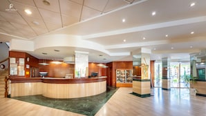 A hotel reception area with a curved counter, a reception desk, and a display of local crafts.