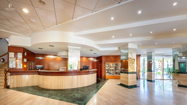 A hotel reception area with a curved counter, a reception desk, and a display of local crafts. - Port Denia Hotel (Denia)