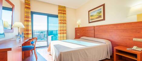 Une chambre d’hôtel avec un grand lit, un bureau avec une chaise, une petite table et une vue sur la ville.