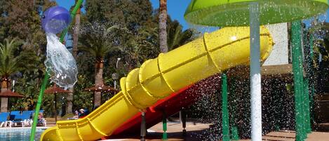 Un parque acuático con un tobogán amarillo y una cubierta verde.