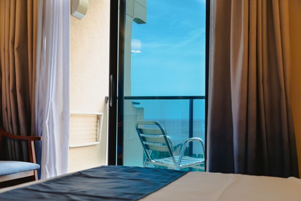 A hotel room with a bed, a chair, and a balcony with a chair. - Port Denia Hotel (Denia)