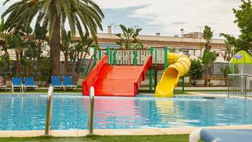 A swimming pool with slides and lounge chairs.