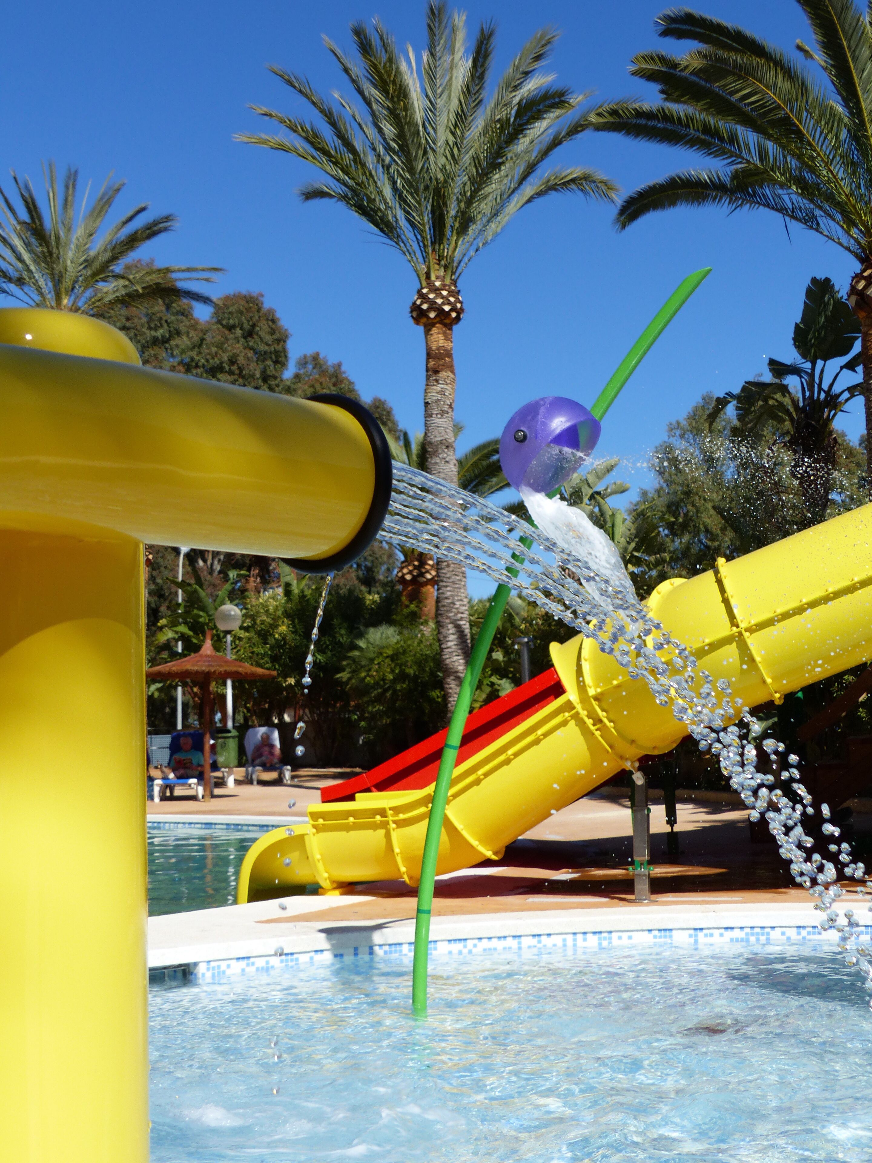 Un parque acuático con un tobogán amarillo y una piscina.