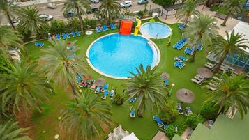 Una grande piscina all'aperto circondata da palme e lettini.