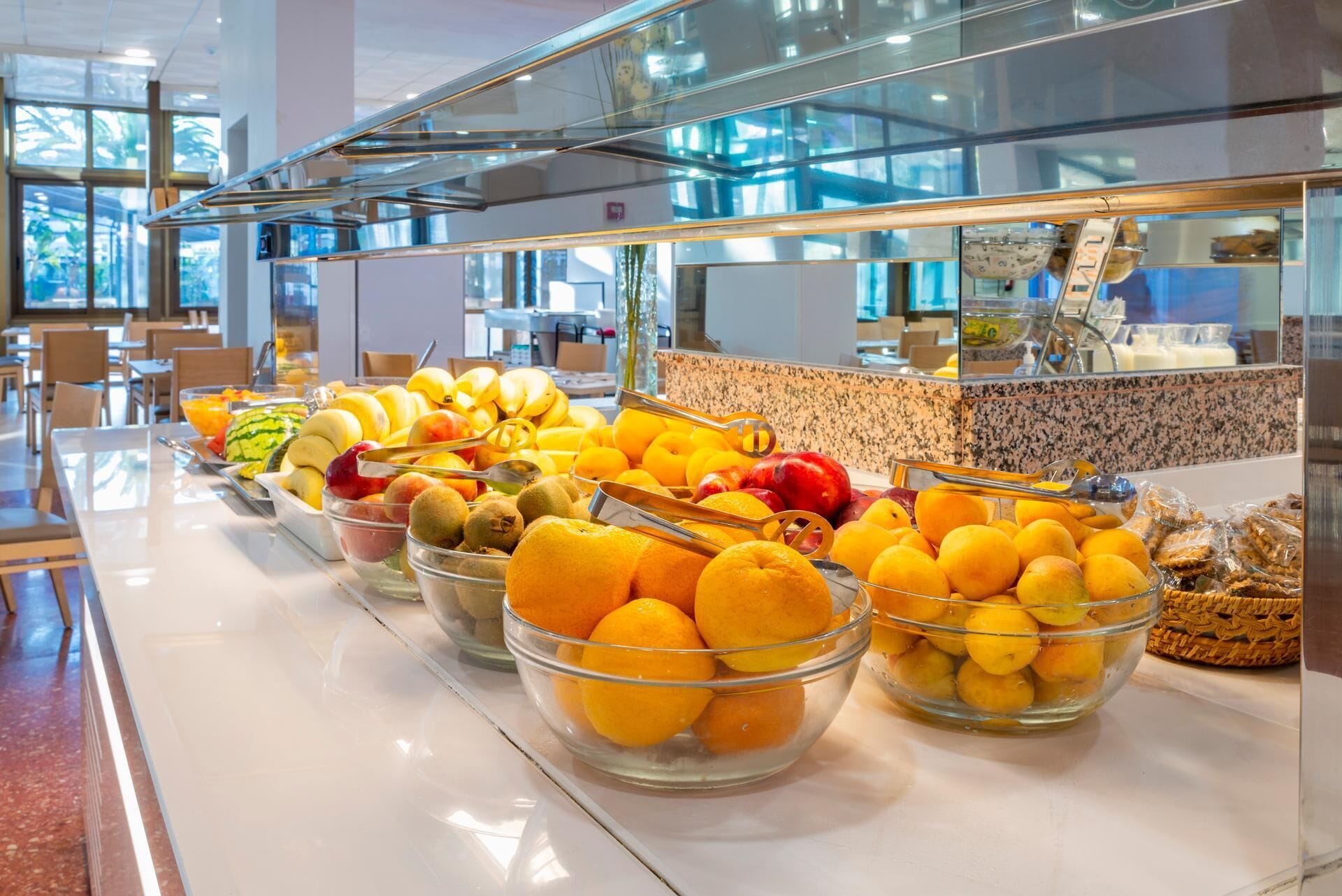 A buffet with various fruits and a kitchen area in the background.