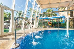 Une piscine intérieure avec des parois en verre transparent, un sol carrelé et une bouée de sauvetage.
