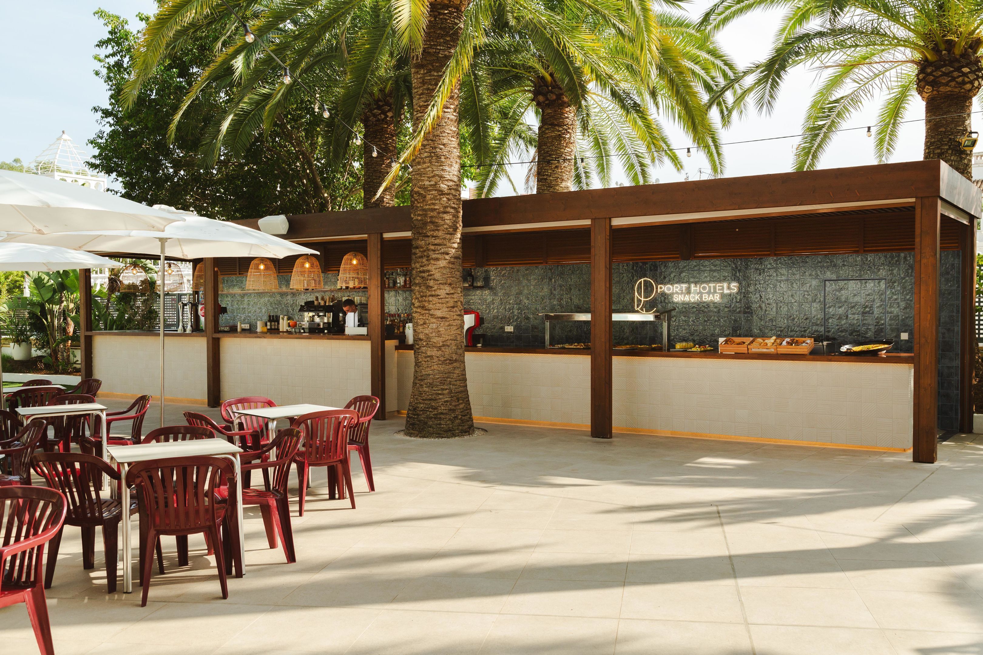 Un espace extérieur aménagé avec des tables et des chaises, un comptoir de bar et des palmiers.