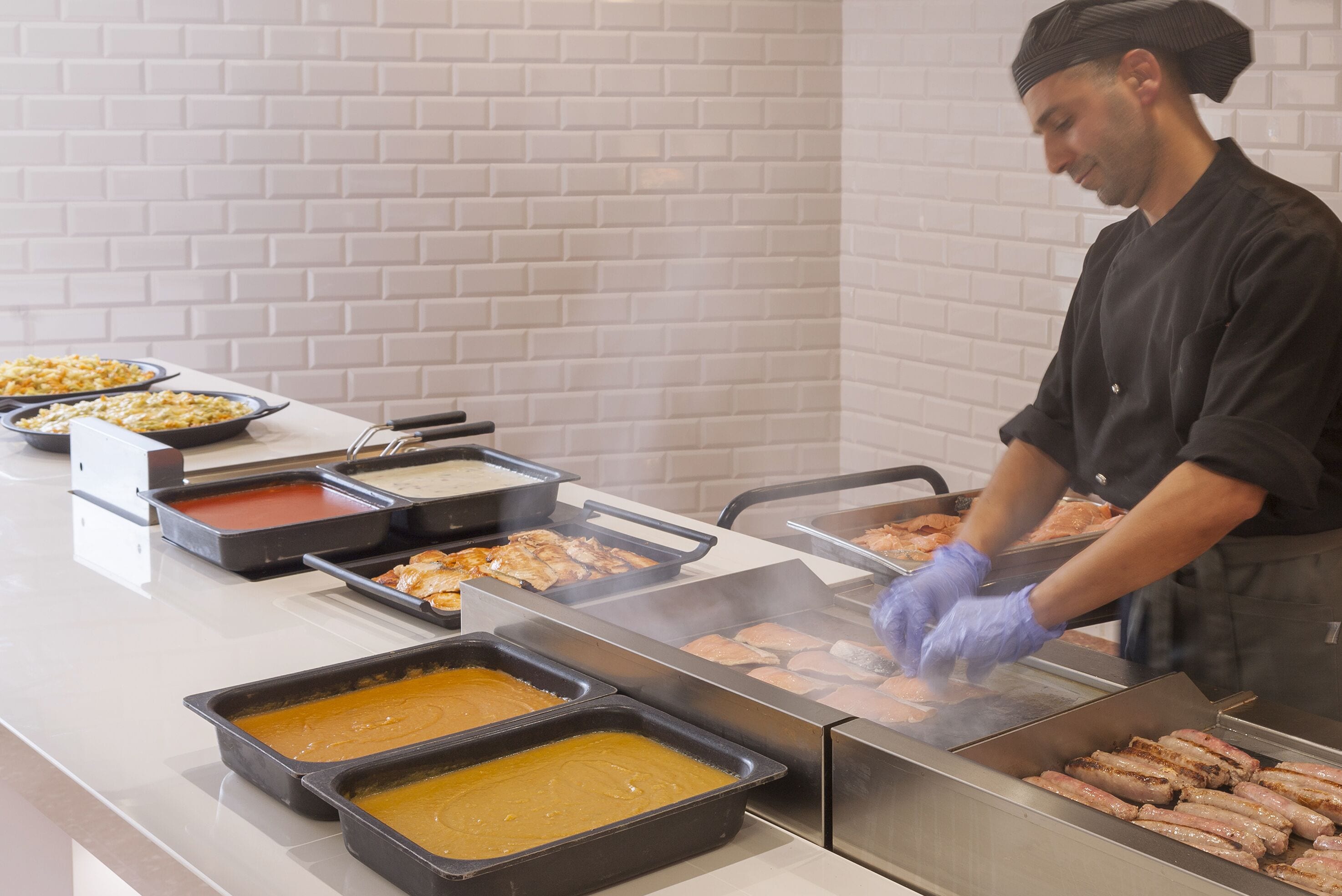A buffet setup with various food items being cooked on a grill.