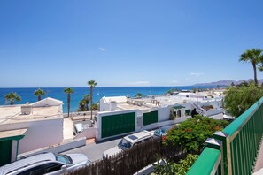 Un área residencial costera con edificios blancos, contraventanas verdes y una vista despejada del mar.
