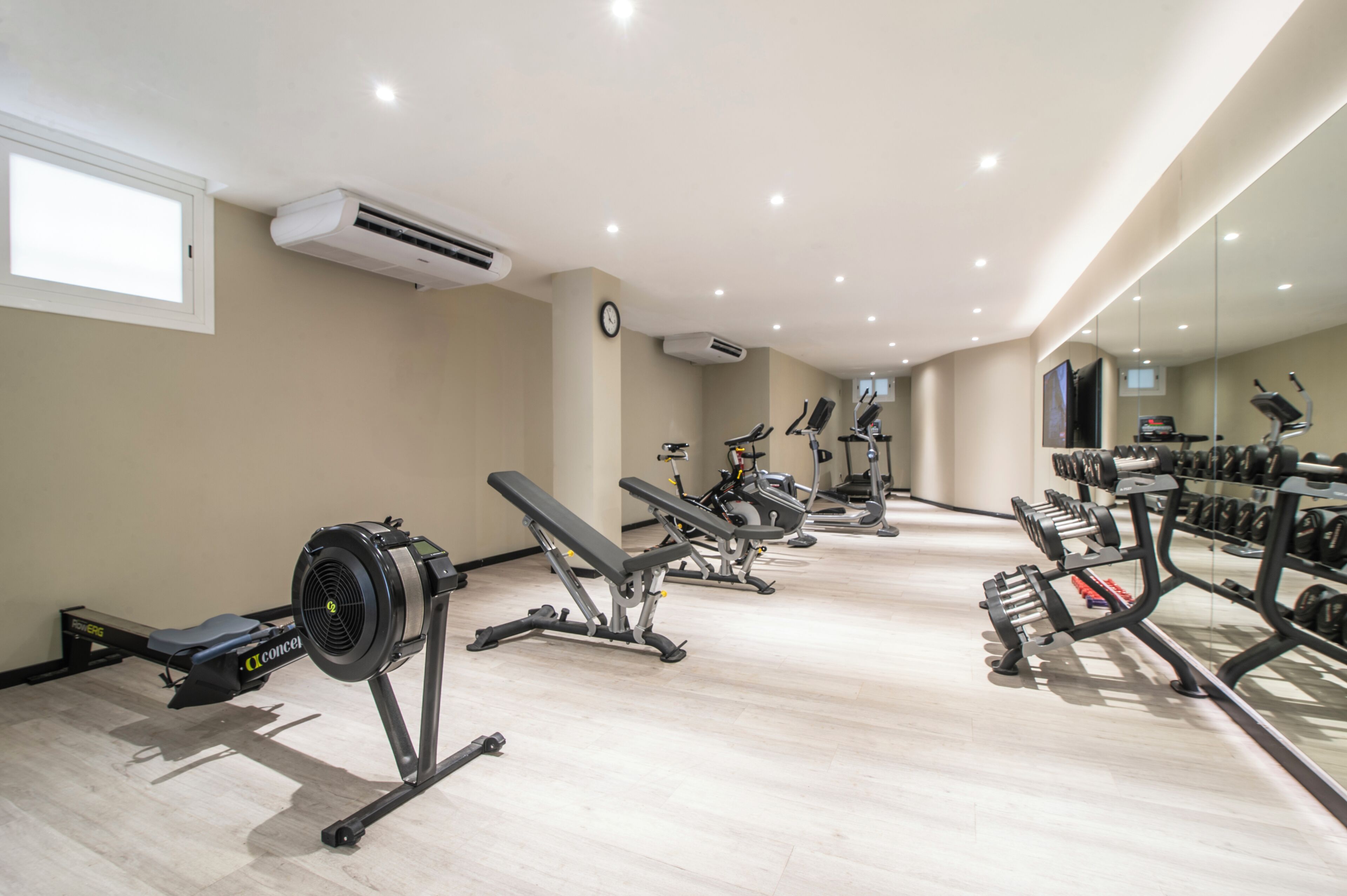 A gym with exercise equipment, a clock, and a large mirror.