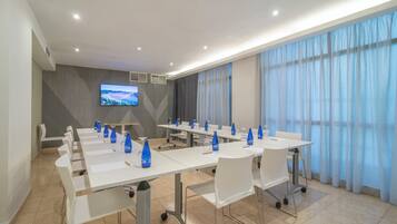 A conference room with a long table, chairs, and a TV screen.