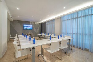 A conference room with a long table, chairs, and a TV screen.