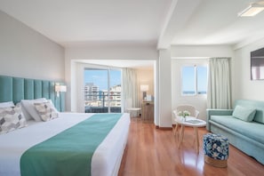 Relax in a stylish room with a large bed, sofa, and ottoman, offering a city view.