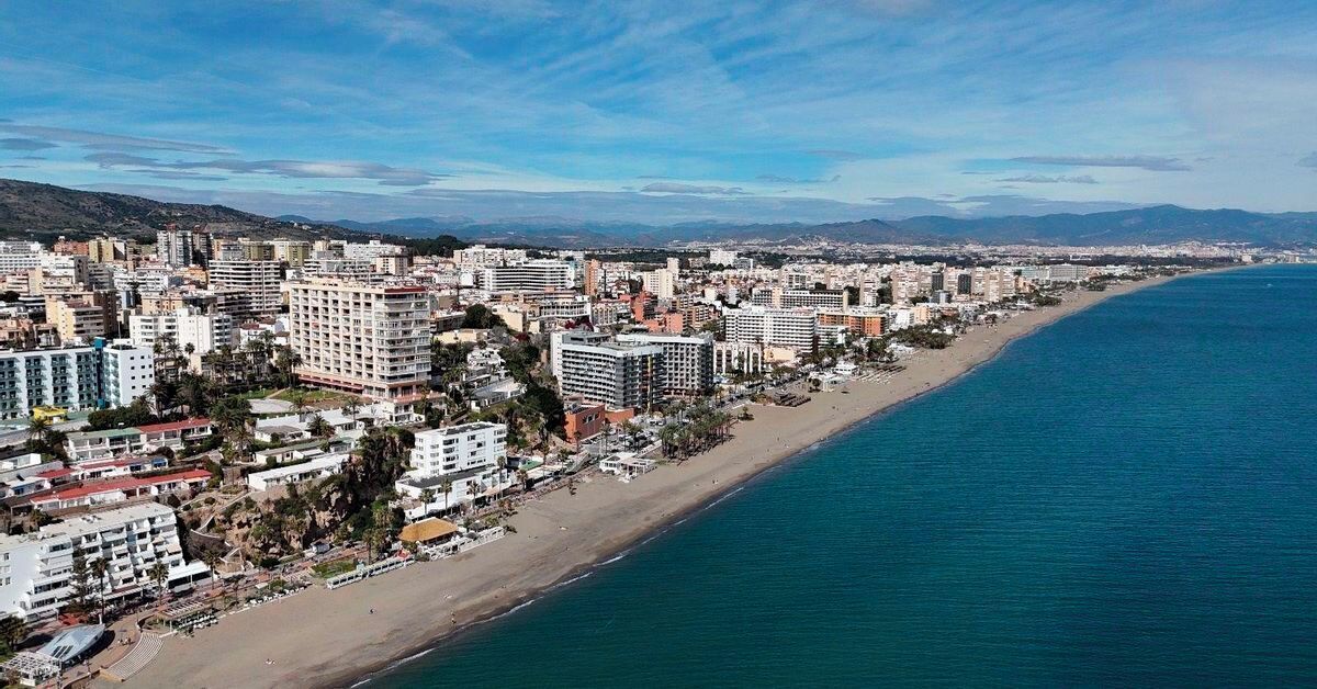 A coastal cityscape with a long beachfront, high-rise buildings, and a clear sky.