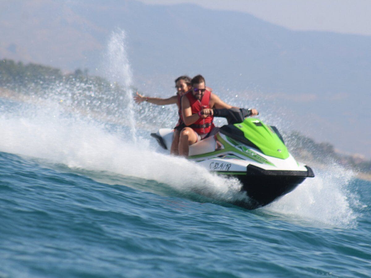 A jet ski with two people on it, moving through water.