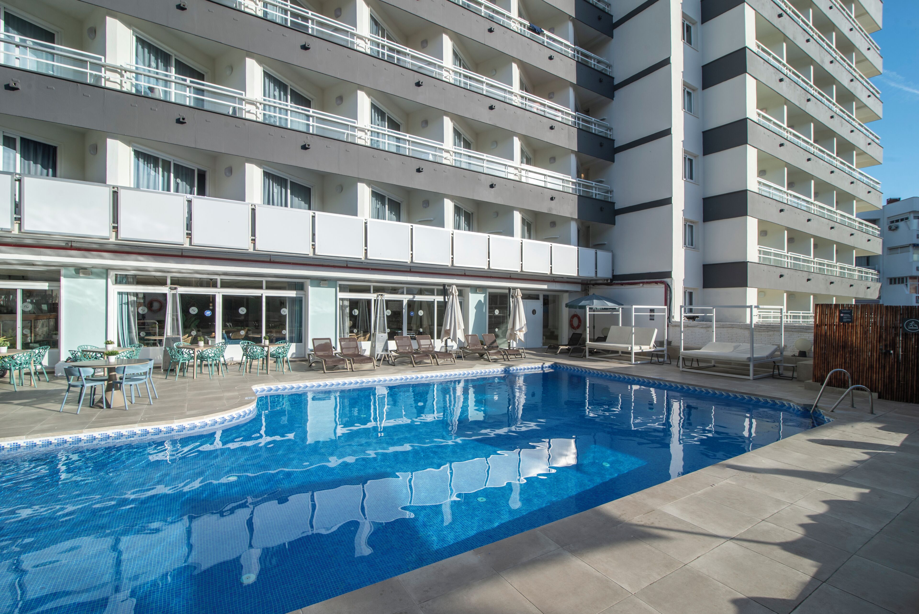 Un hotel con piscina, zona de estar al aire libre y un edificio de varios pisos.