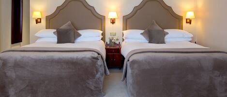 A double bed with a headboard, two bedside lamps, and a nightstand with a vase.