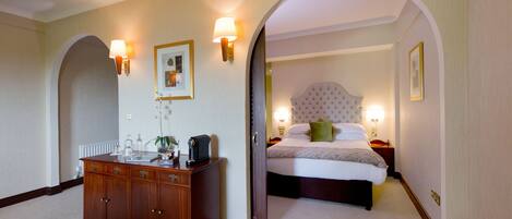Una habitación de hotel con una cama grande, un aparador y dos lámparas fijadas a la pared.