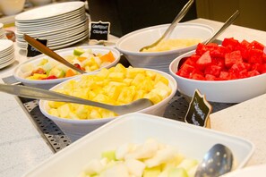 A buffet with various fruit options including pineapple, watermelon, and mixed fruits.