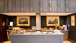 A breakfast buffet with various food items and beverages, framed artwork on the walls, and a modern interior design.