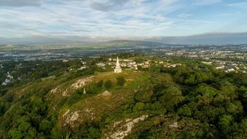 Vista panorámica de un pueblo con una iglesia destacada en una colina, rodeado de vegetación y zonas residenciales.