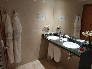Un bagno moderno con due lavandini, uno specchio grande e uno stendibiancheria per accappatoi.