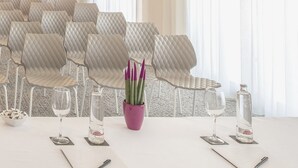 A dining table set with white chairs, a purple vase with green plants, and two bottles of water. - Hotel RH Sorolla Centro By Hoteles RH (Valencia)