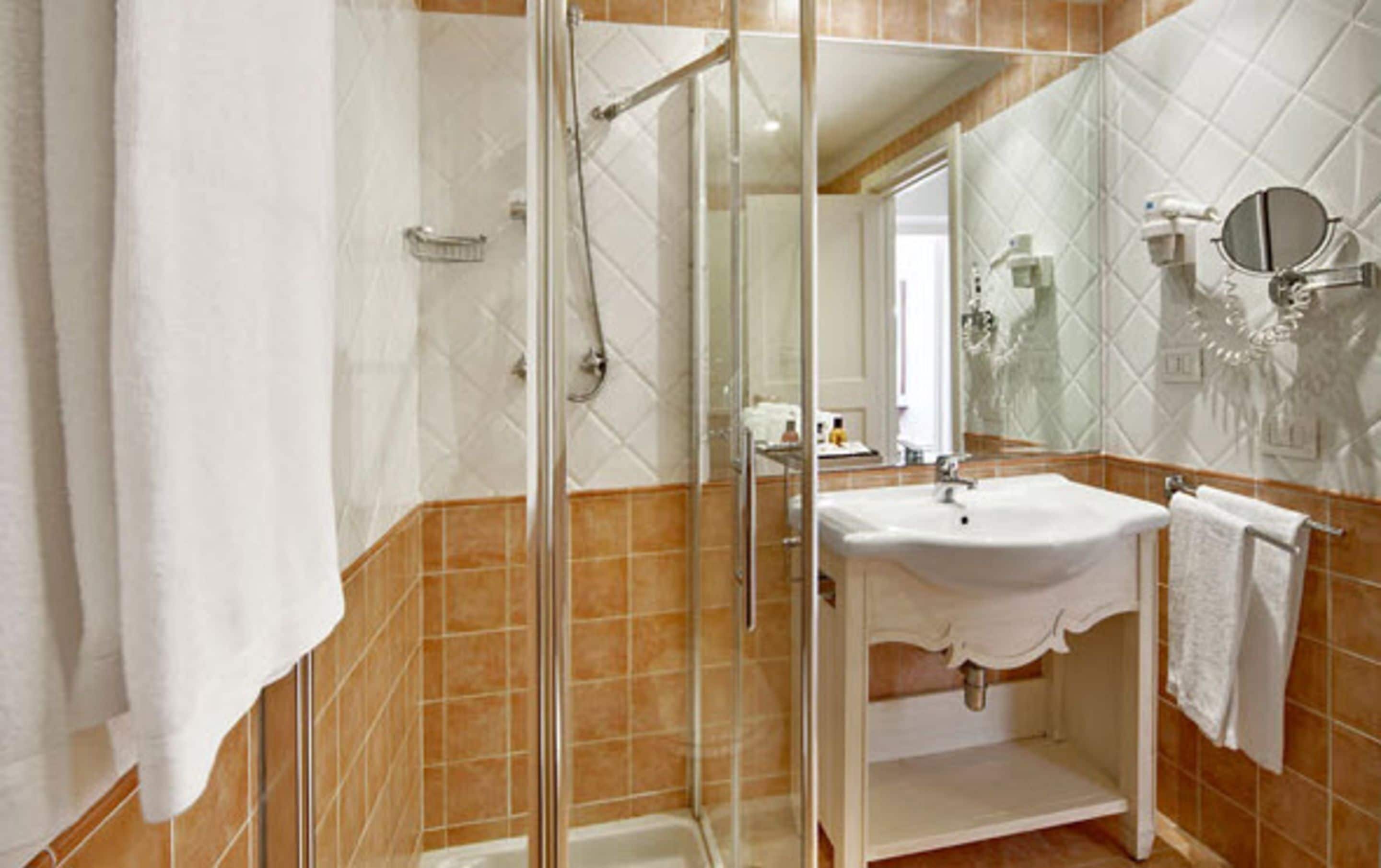 Une salle de bain avec une douche à parois de verre, un lavabo blanc et un miroir.
