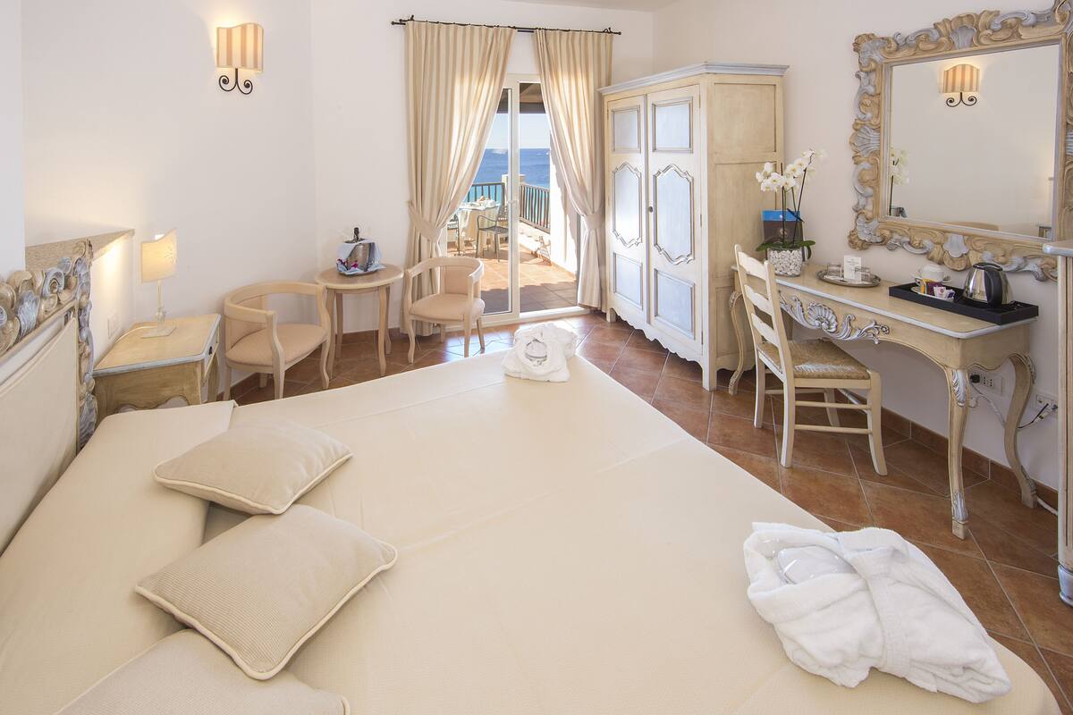 Une chambre d’hôtel avec un grand lit, un bureau, une chaise, une armoire et une vue sur la mer.