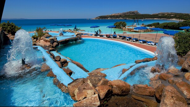 Una piscina con elementos acuáticos y vistas al mar.