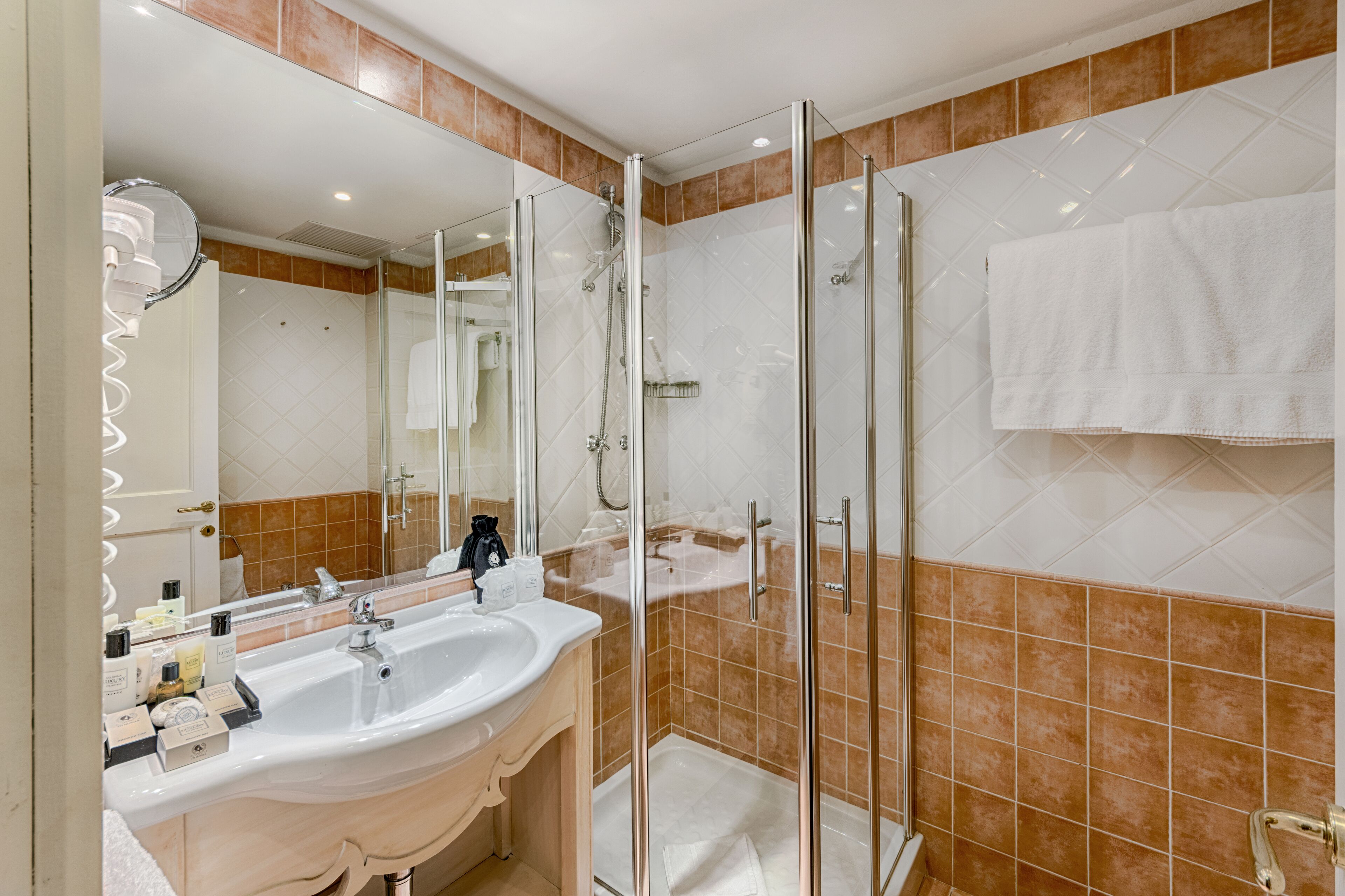 Une salle de bain moderne dotée d’une douche à parois de verre, d’un grand lavabo et d’un miroir.