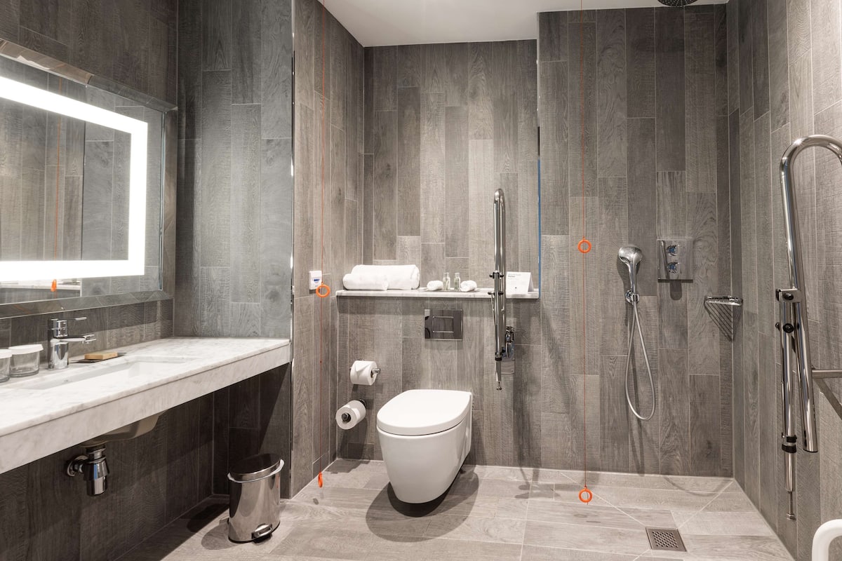 A modern bathroom with a shower, toilet, and sink.