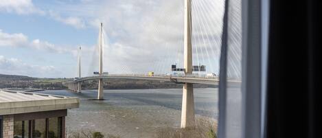 Vista de un puente con cables, un río y un edificio en primer plano.