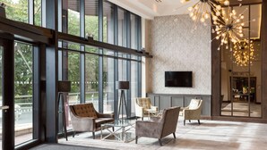 A spacious lobby with large windows, modern furniture, and a unique chandelier. - DoubleTree by Hilton Edinburgh - Queensferry Crossing (Dunfermline)