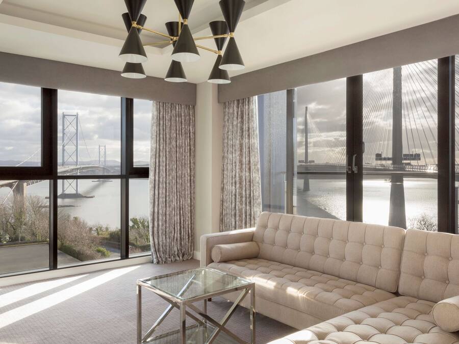 A modern living room with a large window offering a view of a bridge and water.