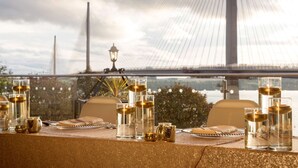 A table set with glasses and a lantern, overlooking a bridge and water. - DoubleTree by Hilton Edinburgh - Queensferry Crossing (Dunfermline)