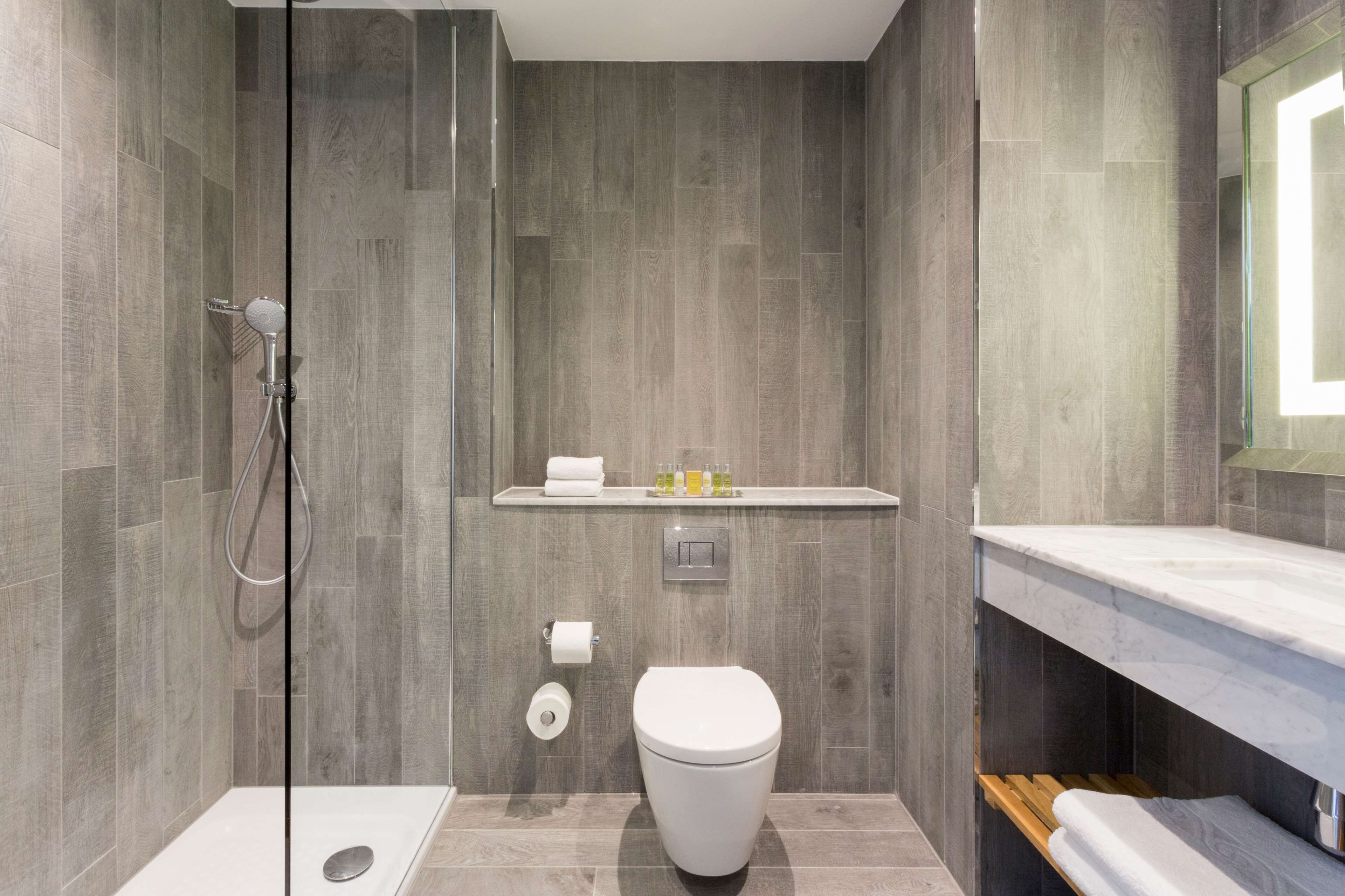 Une salle de bain moderne équipée d’une douche, de toilettes et d’un meuble-lavabo.