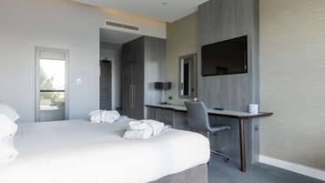 Una habitación de hotel moderna con una cama grande, un escritorio, una silla y un televisor de pantalla plana montado en la pared.
