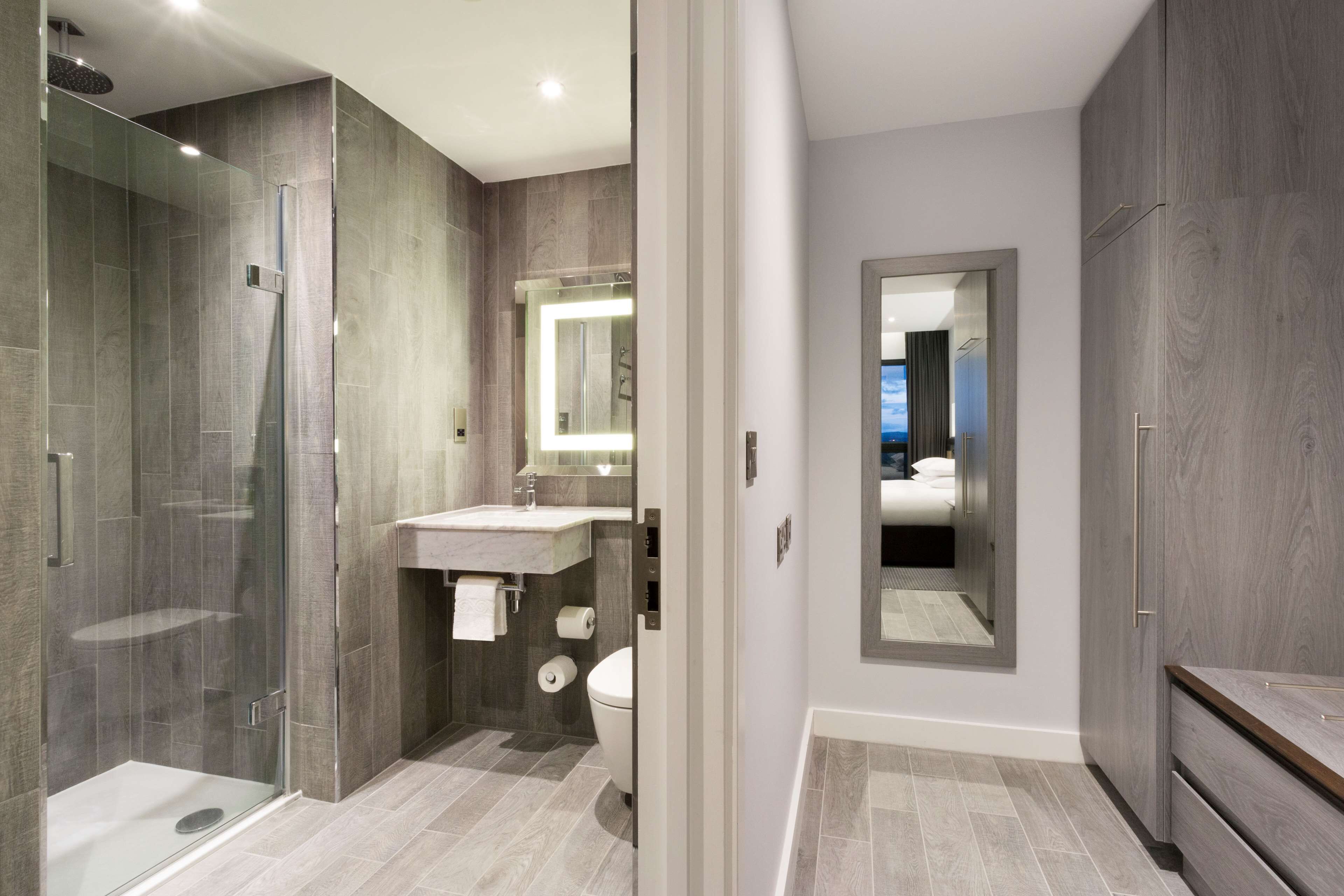 A modern bathroom with a glass-enclosed shower, a vanity with a mirror, and a toilet.