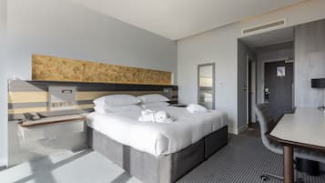 Ein modernes Hotelzimmer mit einem großen Bett, Nachttischen, einem Schreibtisch und einer Duschkabine.